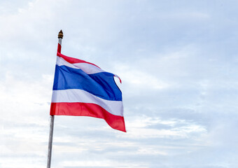 thailand flag striped red, blue and white flies against the sky