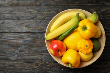 Bowl with vegetables and fruits on wooden background