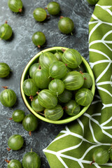 Bowl of gooseberry and kitchen towel on black smokey table