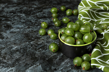 Bowl of gooseberry and kitchen towel on black smokey table