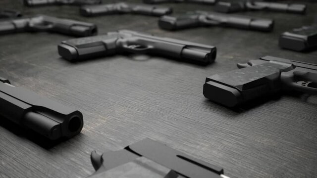 Many modern metallic handguns lying on a grey table against black background  