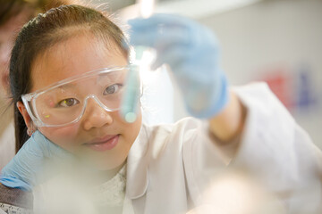 Girl students conducting scientific experiment, examining liquid in test tube in laboratory...