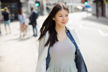 Serious, pensive young woman walking on urban street