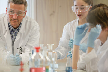 Male teacher and students conducting scientific experiment in laboratory classroom