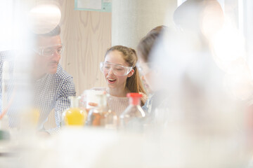 Male teacher and students watching chemical reaction, conducting scientific experiment in laboratory classroom