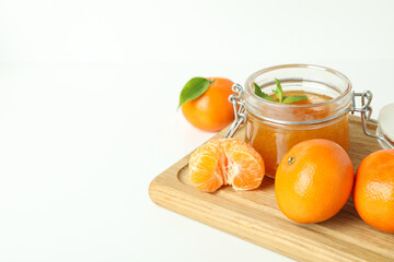 Board with mandarin jam and ingredients on white background