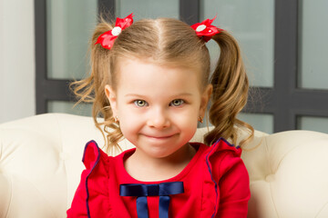 Cute blonde little girl sitting on comfy armchair