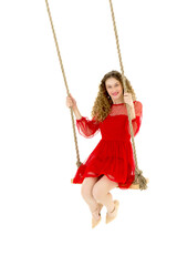 Beautiful girl in red nice dress swinging on swing