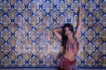 Middle-aged Hispanic woman in a red colored dress with rhinestones to belly dance, making figures...