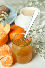 Concept of tasty breakfast with mandarin jam on white textured table