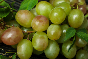 Green grape with leaves on wooden background, close up