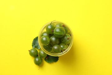 Jar of ripe gooseberry on yellow background