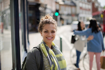 Portrait smiling young woman on sunny urban street