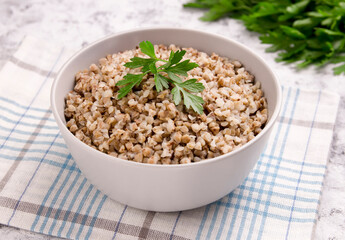 Freshly cooked buckwheat porridge in a plate on a gray background.
