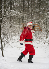 Winter holiday. The vital life. Santa Claus with a sleigh walking in a snowy woods.