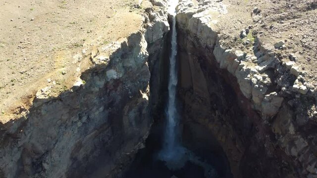 Fly above mountainous waterfall in Dangerous canyon at Kamchatka volcano national park. Mutnovsky volcano valley.