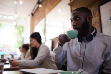 Young man with headphones drinking coffee in cafe
