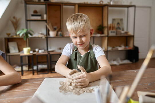 Little boy works with clay, kid in workshop