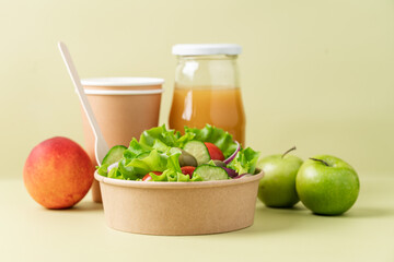 Healthy vegetable salad in recyclable cardboard container. Food delivery, healthy food menu for home or office concept. Green background, side view