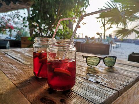 Cold non alcoholic drinks on a table. Local unidentified bar in Cape Verde. Tropical climate and warm evening. Selective focus on the glasses, blurred background.