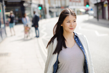 Serious, pensive young woman walking on urban street