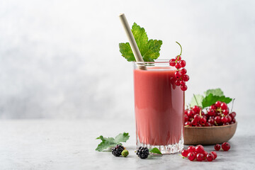 Red currant, raspberry, blackberry and blueberry smoothie. Transparent glass of berry healthy drink with bamboo tube