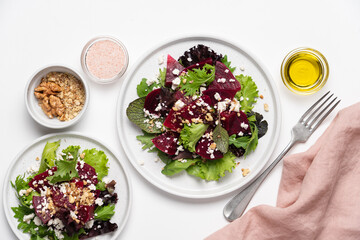 Beetroot salad with feta cheese and walnuts. Vegetable salad in plate on white background, top view