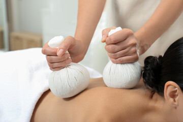 Young woman receiving herbal bag massage in spa salon, closeup