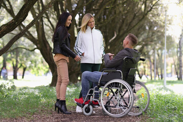 Man in wheelchair and laughing woman chatting in park