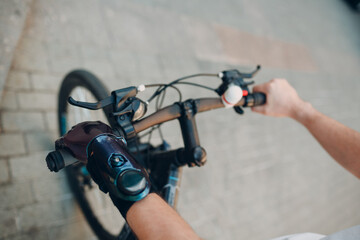 Young disabled man with artificial prosthetic hand in casual clothes riding bicycle