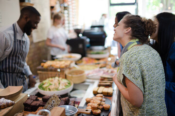 Male worker helping female customers in cafe