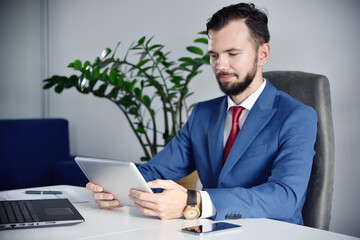 Obraz premium Office manager sitting in office and using tablet computer.
