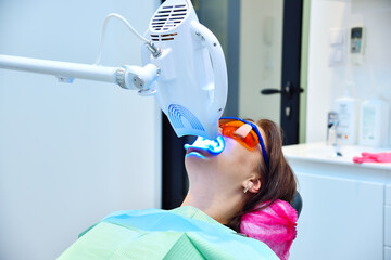 Teeth whitening procedure with ultraviolet light lamp.