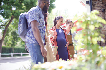 Fototapeta premium Female florist helping friends at sunny flower shop storefront