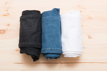 Different types of jeans rolled into a roll. Jeans of different colors on a light wooden background. Jeans texture.