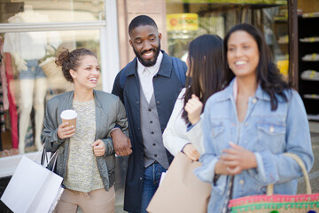 Obraz premium Smiling friends with coffee and shopping bags