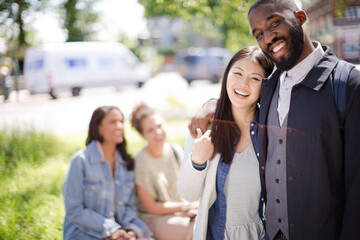 Portrait smiling, affectionate young couple hugging in sunny park