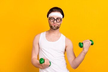 Portrait of attractive funky guy nerd doing work out muscles development isolated over bright...