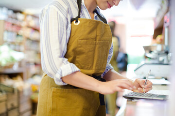 Female cashier using calculator in grocery store