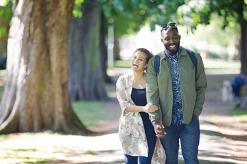 Obraz premium Young couple holding hands, walking in park
