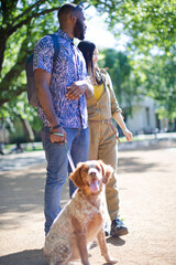 Happy young couple walking dog in sunny park