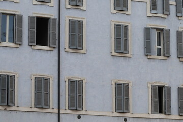 Fototapeta na wymiar Light Blue Building Facade Detail with Windows and Shutters in Rome, Italy