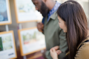 Young couple browsing real estate listings at storefront