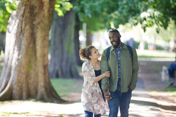 Fototapeta premium Young couple holding hands, walking in park