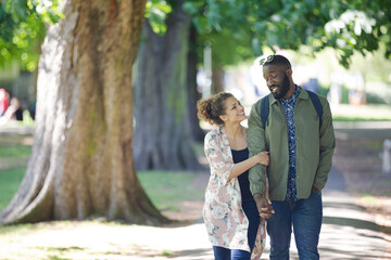 Fototapeta premium Young couple holding hands, walking in park