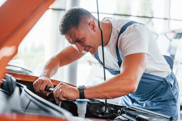 Fototapeta na wymiar Man in uniform is repairing broken automobile indoors