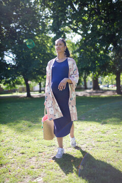 Pregnant woman walking in sunny park