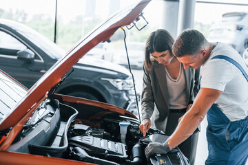Plakat Showing results of work. Man repairing woman's automobile indoors. Professional service