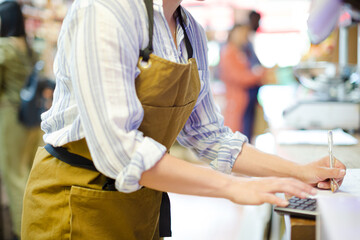 Fototapeta premium Female cashier using calculator in grocery store