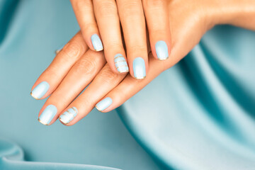 Beautiful female hands with blue manicure and sparkles. Colored French manicure with sparkles.